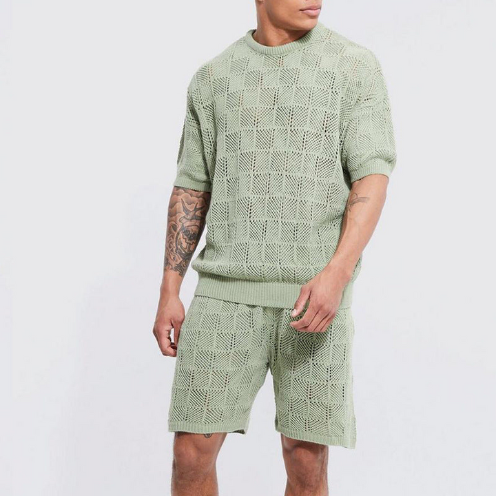 A person wearing a matching sage green casual 2 piece set—short sleeve shirt and shorts—with a geometric open-knit pattern, standing against a plain light background.