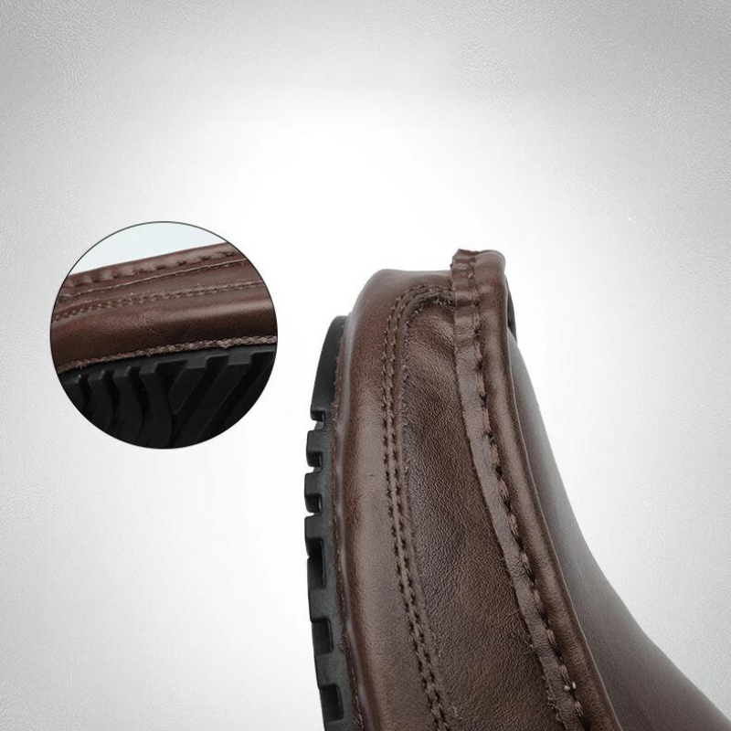 Close-up of a genuine leather loafer with visible hand-stitched moccasin detailing and a textured black rubber sole; inset shows a zoomed view of the stitching and sole detail.