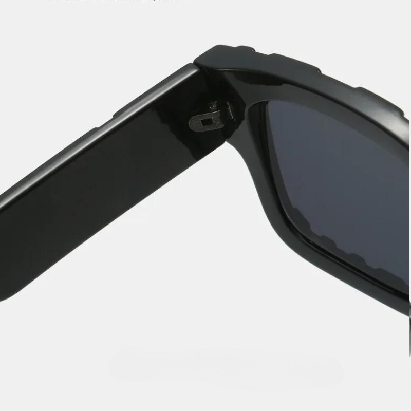 Close-up of the hinge area of vintage sunglasses in black, featuring one arm partially folded and dark tinted lenses with UV400 protection, set against a light gray background.