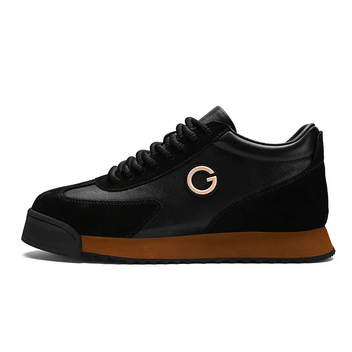 A black sneaker with a brown sole, black laces, and a metallic G logo on the side. These sleek sneakers feature luxe leather suede textures, a slightly elevated heel, and a modern design perfect for the urban professional.