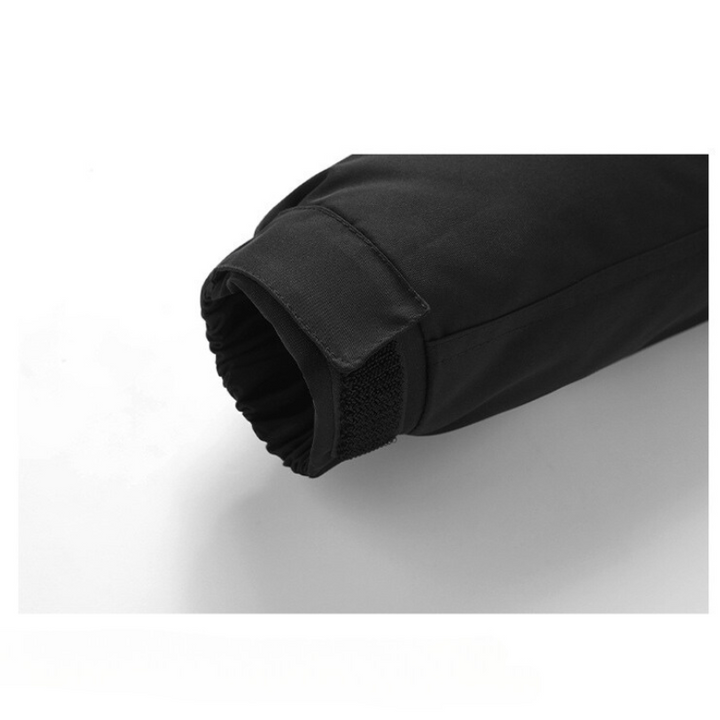 Close-up of the sleeve of a black windproof jacket with adjustable cuffs and an elastic detail, laying on a white surface.