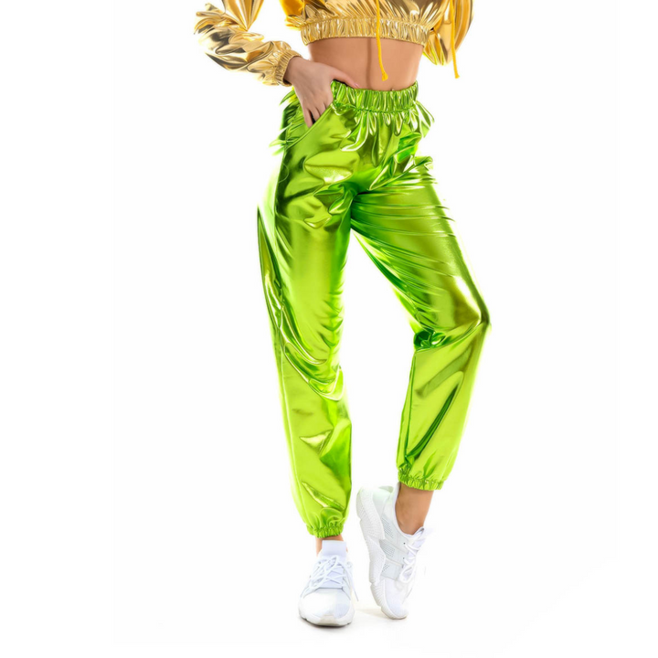 A person wearing shiny neon green jogger pants with an elastic high waist and a metallic gold cropped jacket, paired with white sneakers, stands against a white background. The person’s face is not visible.