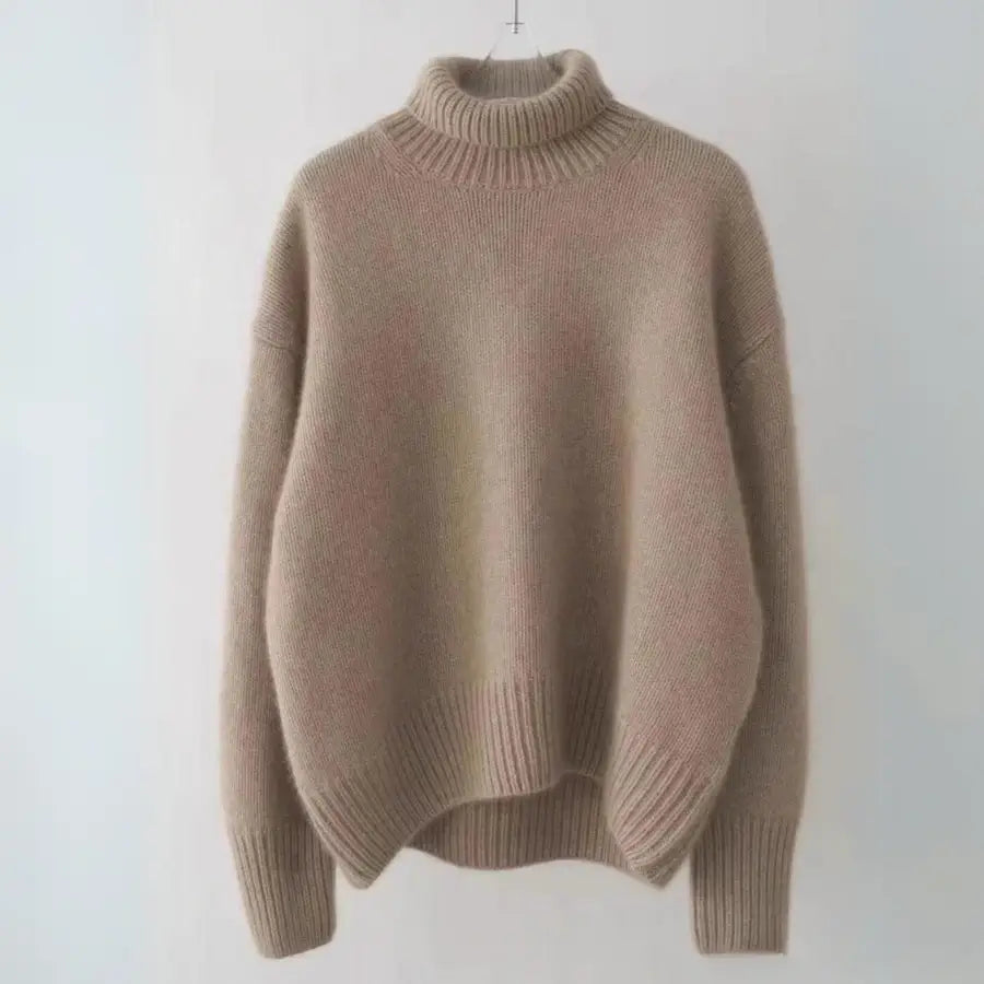 A light brown, cashmere turtleneck sweater with an oversized fit, featuring long sleeves and ribbed cuffs, hem, and collar, hanging against a plain light background.
