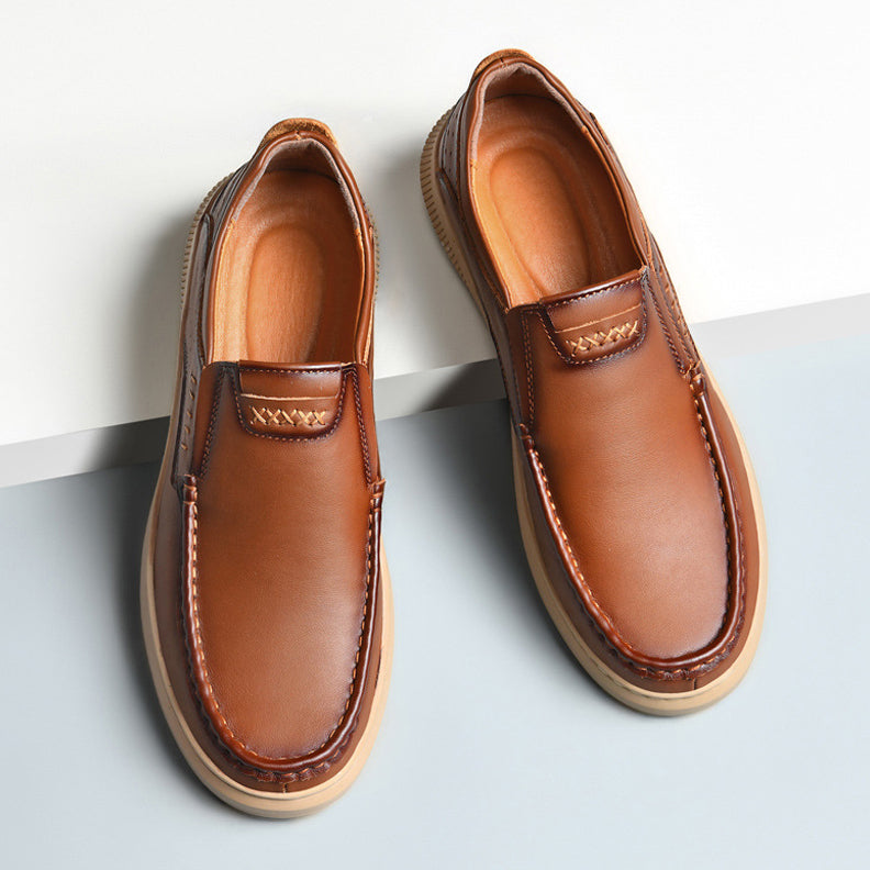 A pair of Men's Cowhide Leather Shoes featuring brown leather, soft soles, and visible stitching, designed in a slip-on loafer style and placed on a light gray and white surface.
