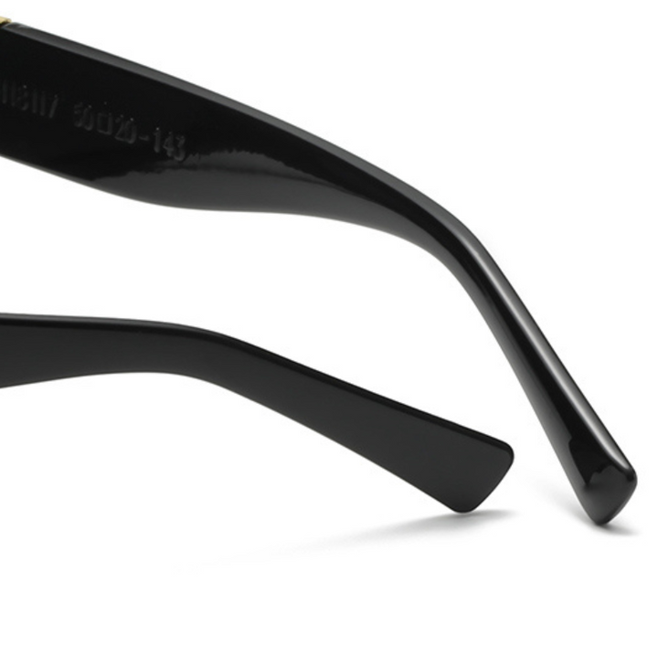 Close-up of the black arms of a pair of designer sunglasses, showing the smooth, glossy finish and slight curve at the ends.