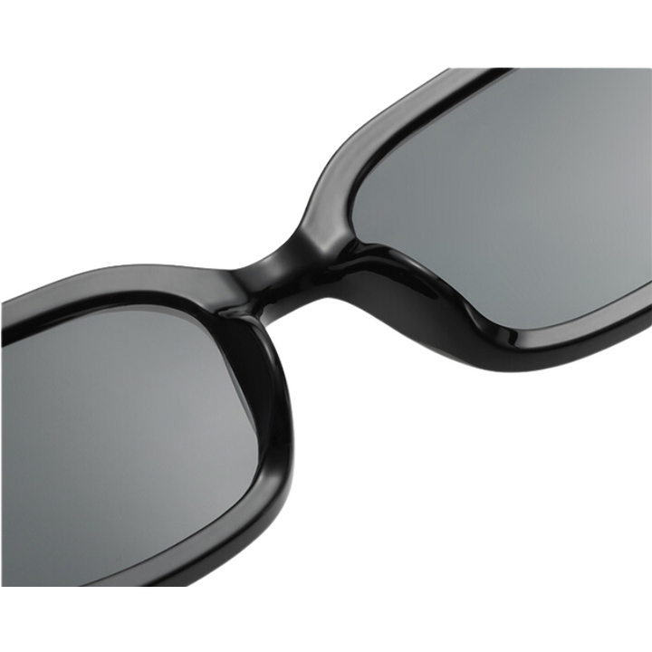 Close-up view of the bridge and lenses of black, rectangular designer sunglasses featuring dark tinted lenses and UV400 protection.
