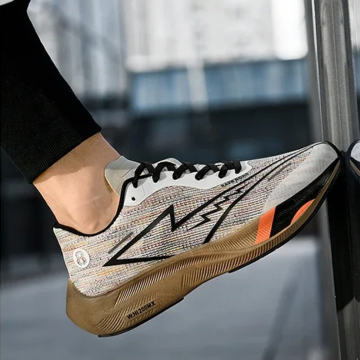 A person wearing a stylish running shoe with a patterned upper, black laces, a bold lightning design, orange accents, and a shock-absorbing sole steps up onto a metal surface.