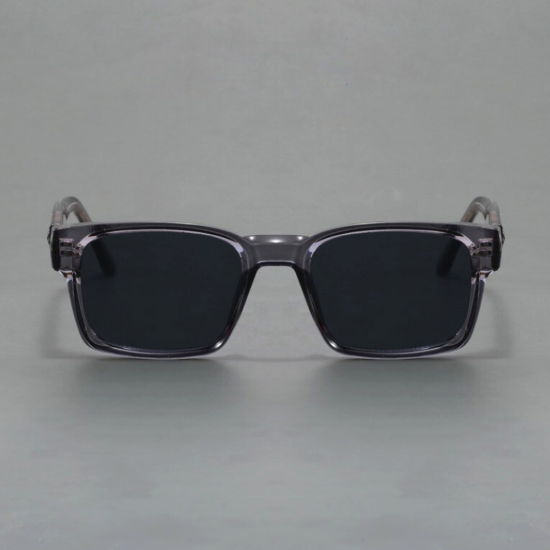 A pair of rectangular, black sunglasses with thick, translucent gray frames and modern design, offering UV400 protection, displayed against a plain gray background.