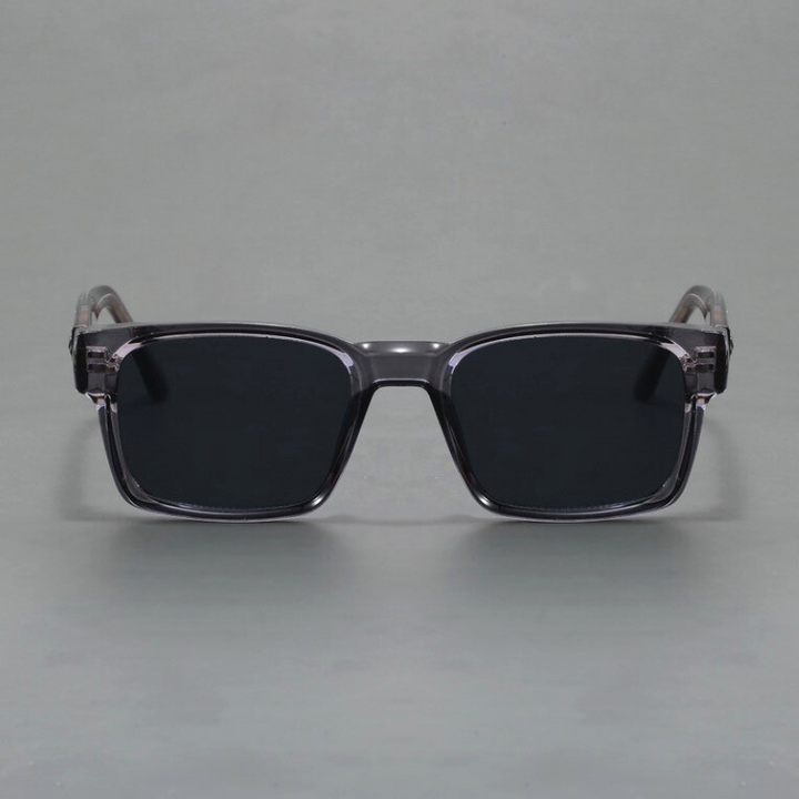 A pair of rectangular, black sunglasses with thick, translucent gray frames and modern design, offering UV400 protection, displayed against a plain gray background.