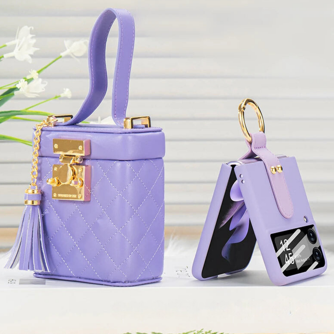 A small, quilted lavender handbag with a gold clasp and tassel sits next to a matching lavender leather phone case with a crossbody strap and gold keyring, both displayed on a white surface.