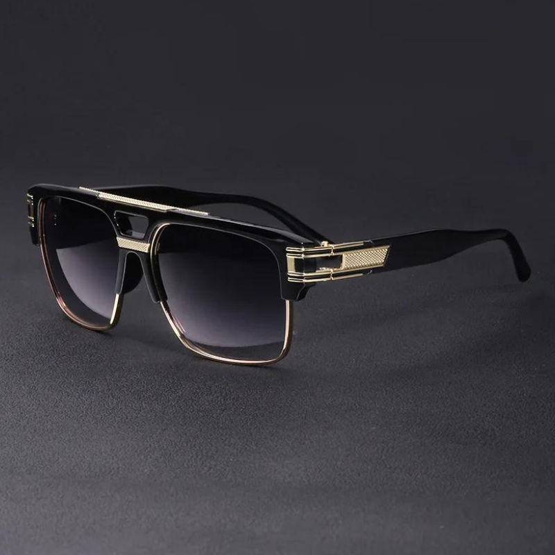 A pair of stylish black and gold geometric sunglasses with rectangular frames and gradient dark lenses, featuring UV400 protection, displayed on a dark surface.