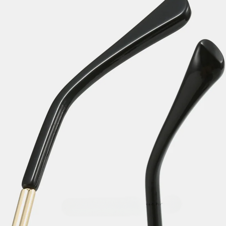 Close-up of two black eyeglass temples with gold hinges, showcasing premium metal frames against a plain white background.