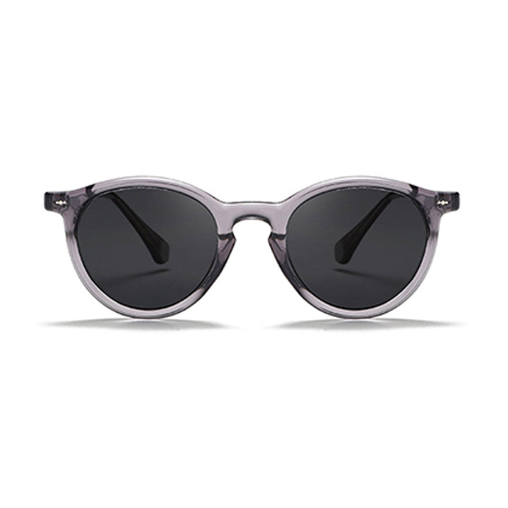 Fashionable eyewear featuring round frame sunglasses with translucent gray frames and dark tinted lenses, shown against a white background.