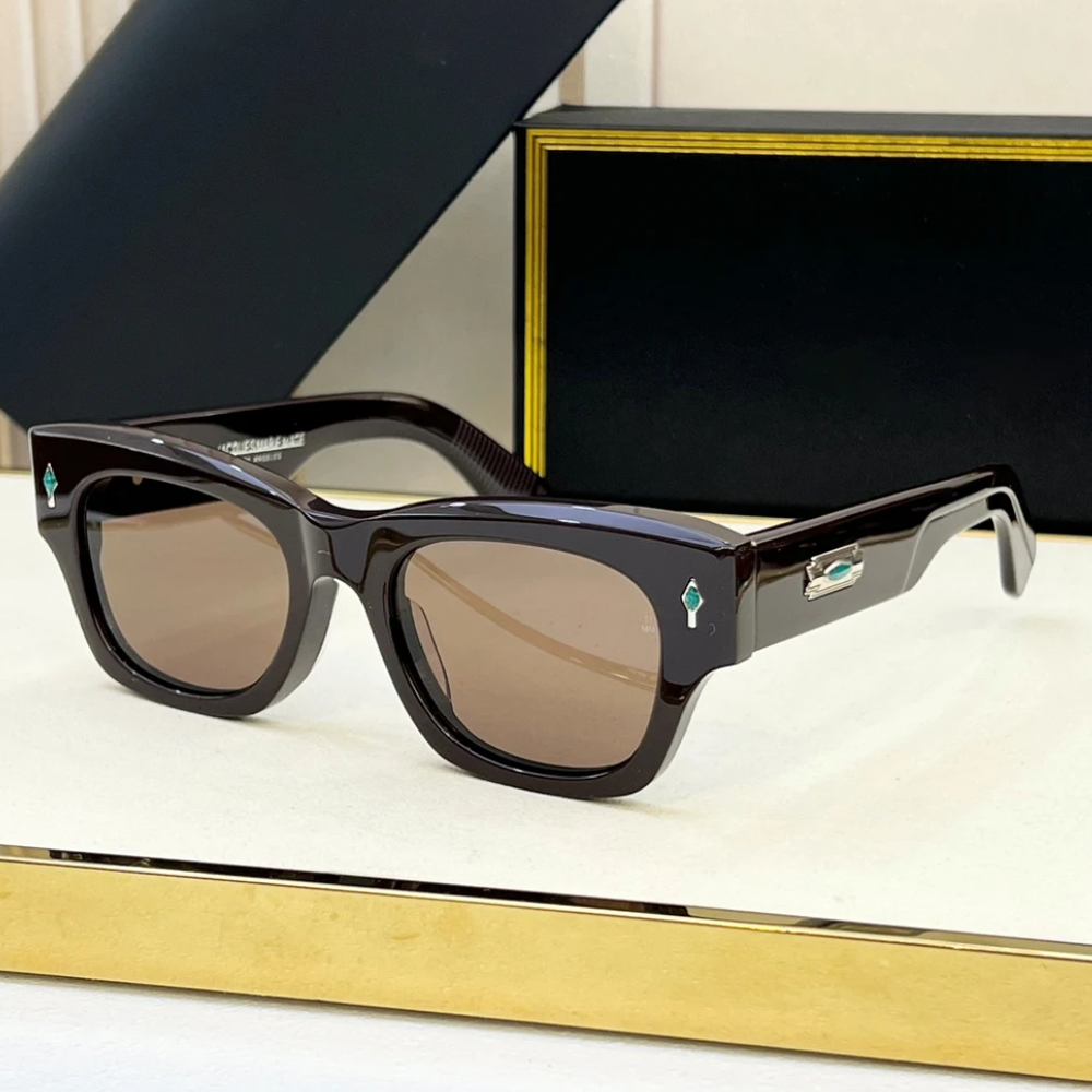 A pair of rectangular, dark brown retro sunglasses with brown tinted lenses sits on a white surface. The temples feature a turquoise detail and a silver accent. A black and gold case is in the background.