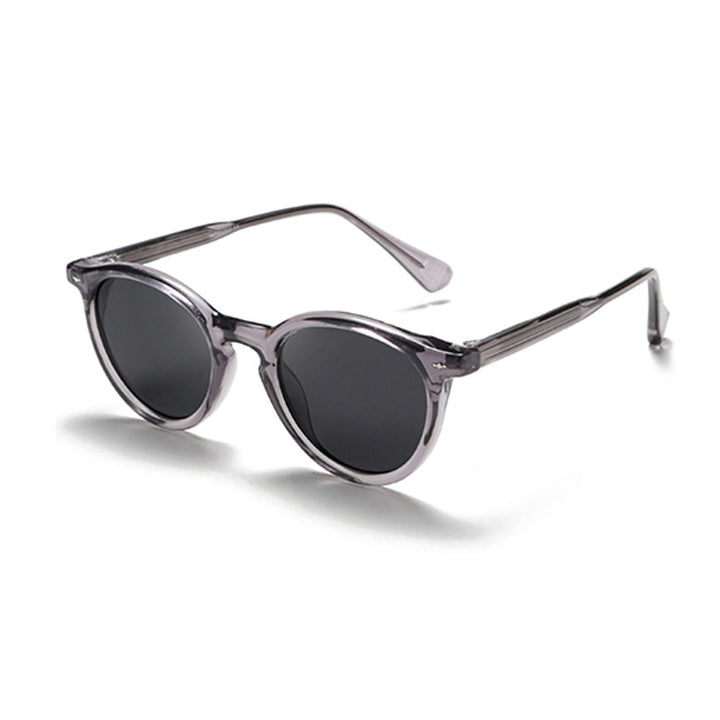 A pair of fashionable eyewear: round frame sunglasses with dark lenses and translucent gray frames, displayed at an angle on a white background.