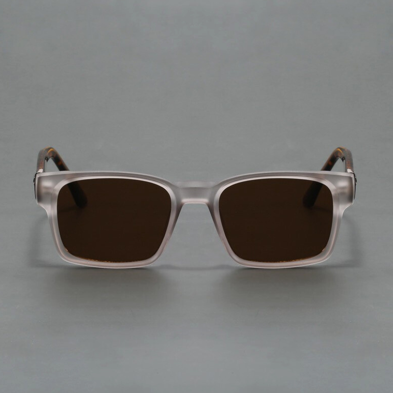A pair of square, transparent-framed sunglasses with a modern design and dark tinted lenses offering UV400 protection, displayed against a plain gray background.
