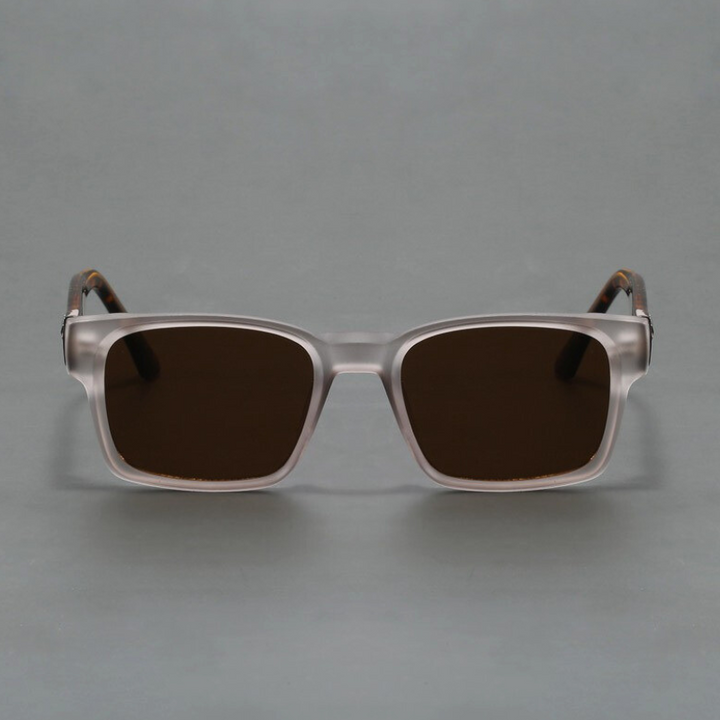 A pair of square, transparent-framed sunglasses with a modern design and dark tinted lenses offering UV400 protection, displayed against a plain gray background.