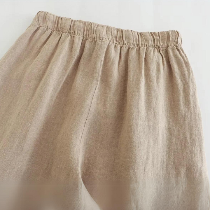 Beige linen wide-leg pants with an elastic waistband, shown from the waist down against a white background. The fabric appears soft and lightweight, perfect for effortless summer style.