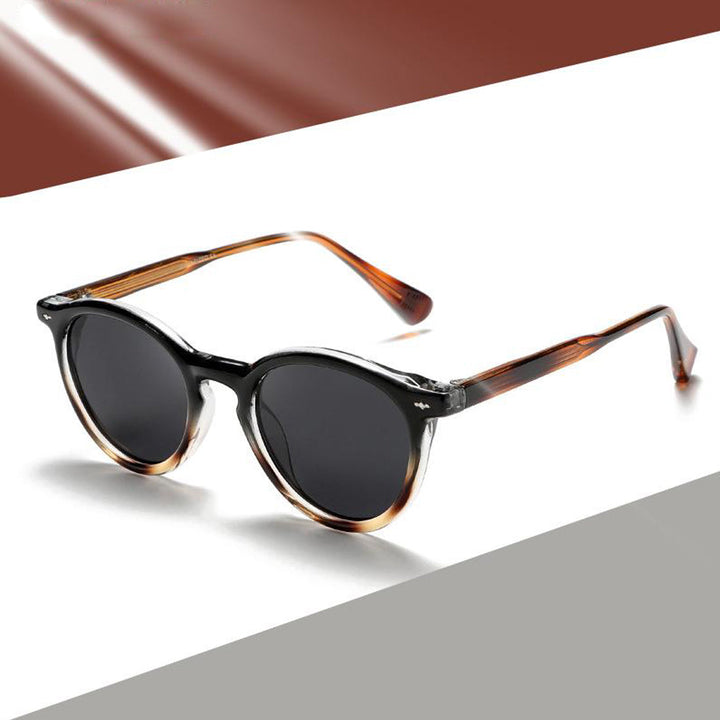 Round frame sunglasses with dark lenses and tortoiseshell frames are displayed against a modern, color-blocked background—perfect for those seeking fashionable eyewear with a stylish edge.
