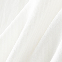 Close-up of soft, white fabric with gentle folds and a slightly textured surface, highlighting the smooth and delicate appearance of this versatile blouse.