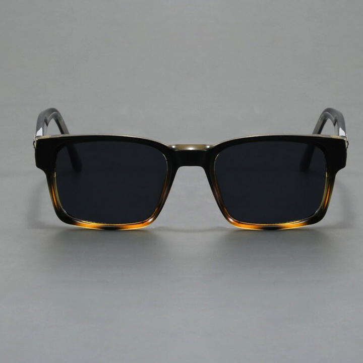 A pair of black rectangular sunglasses with durable frames, dark lenses, and a subtle gradient brown detail at the bottom of the frames, displayed against a plain gray background.