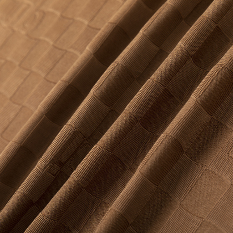 Close-up of brown fabric with a tailored fit, featuring a textured checkerboard pattern and visible folds that highlight its soft, slightly shiny surface.