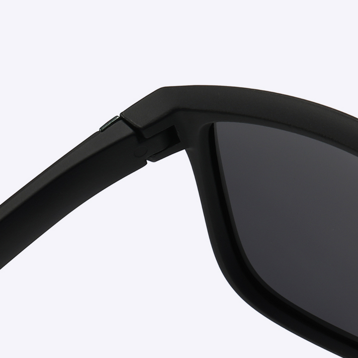 Close-up of the hinge and upper frame of a pair of stylish sunglasses with dark lenses, set against a plain light background.