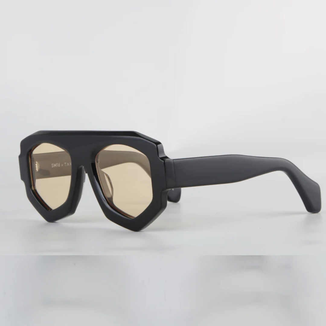Black geometric sunglasses with a bold acetate frame and light brown tinted lenses, featuring UV400 protection, shown against a plain white background.
