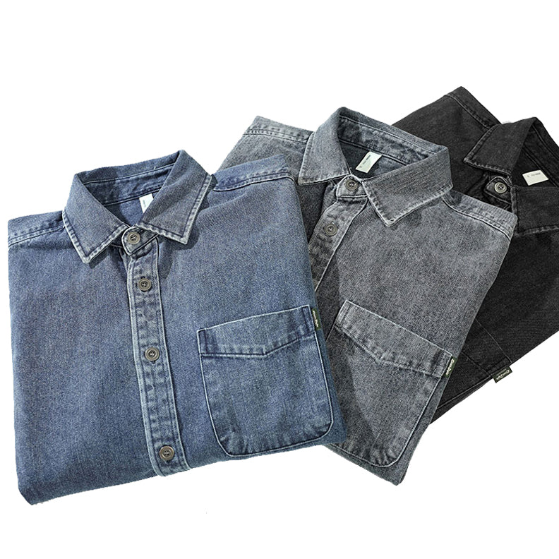 Three folded washed denim overshirts in blue, gray, and black are arranged diagonally on a white background, each with a visible front pocket and buttoned collar.
