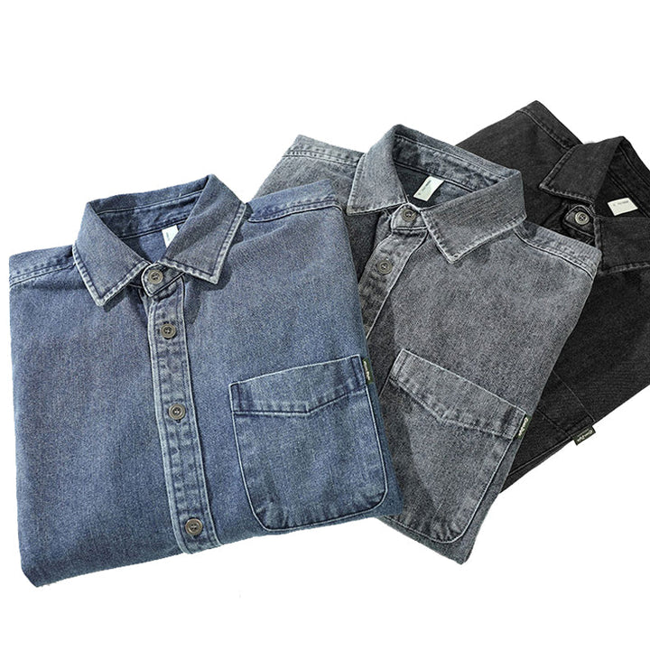 Three folded washed denim overshirts in blue, gray, and black are arranged diagonally on a white background, each with a visible front pocket and buttoned collar.