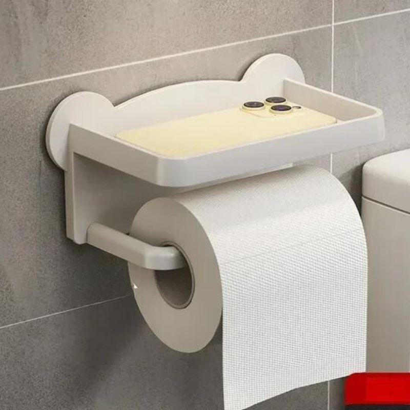 A moisture-resistant, wall-mounted toilet paper holder with a multi-functional shelf for your smartphone is attached to a gray tiled bathroom wall next to the toilet.