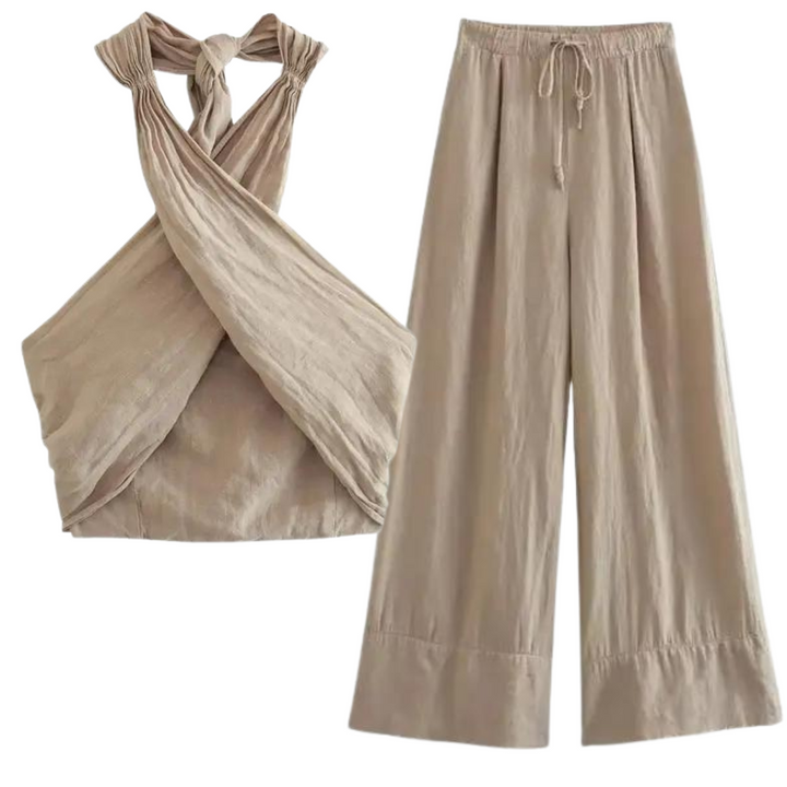 A beige two-piece outfit for effortless summer style, featuring a chic halter collar on the sleeveless, criss-cross top and wide-leg pants with a drawstring waist, both crafted from lightweight, textured fabric.