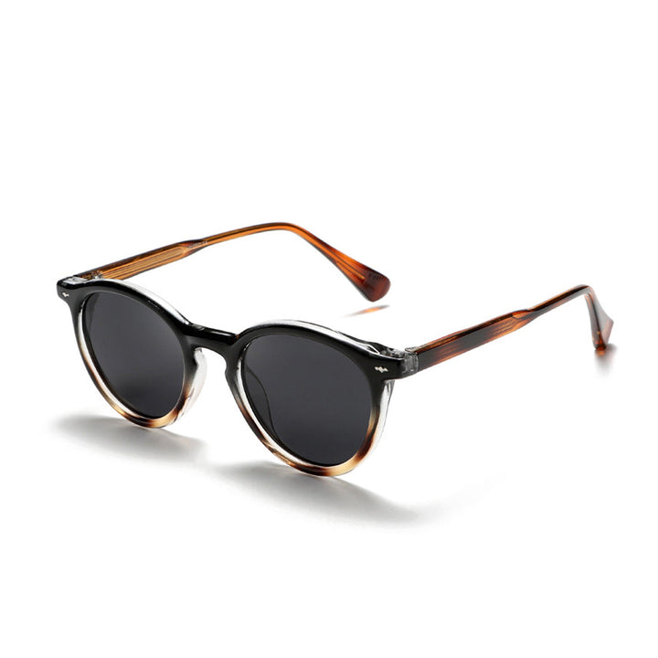 Round Frame Sunglasses with black lenses and a dark brown to clear gradient frame, paired with brown arms, create fashionable eyewear perfect for any look. Displayed on a white background.