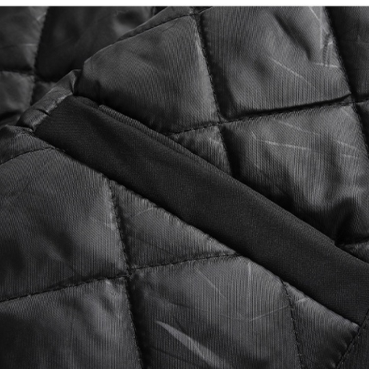 Close-up of black quilted fabric with diagonal stitching and a smooth black band crossing the center, showcasing the slightly shiny texture and geometric pattern of this windproof jacket.