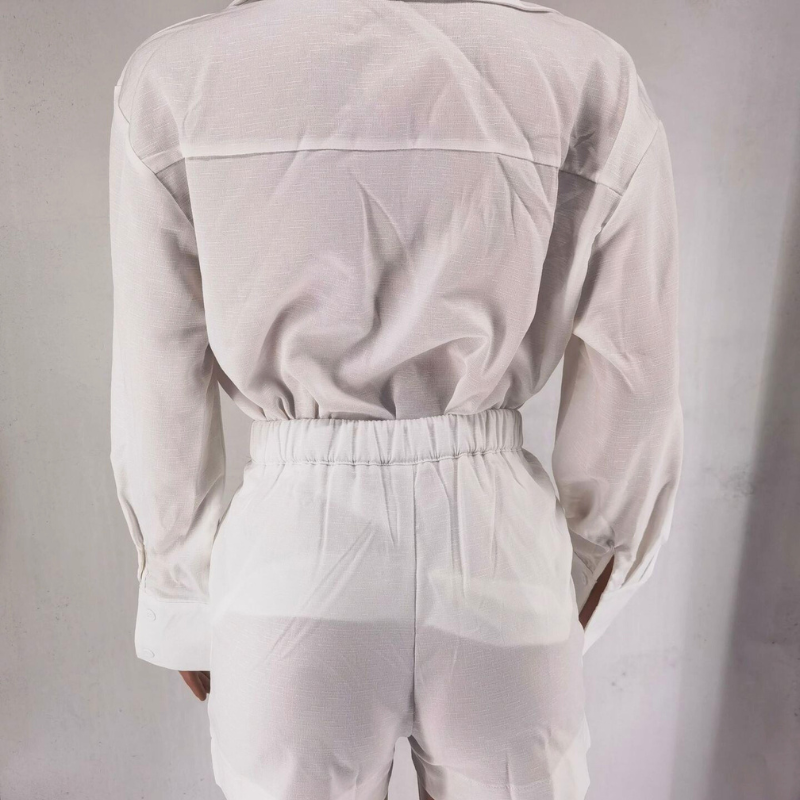 Person wearing a white long-sleeve linen set and high-waisted pants, photographed from the back against a plain light background. The sustainable linen fabric appears slightly sheer.