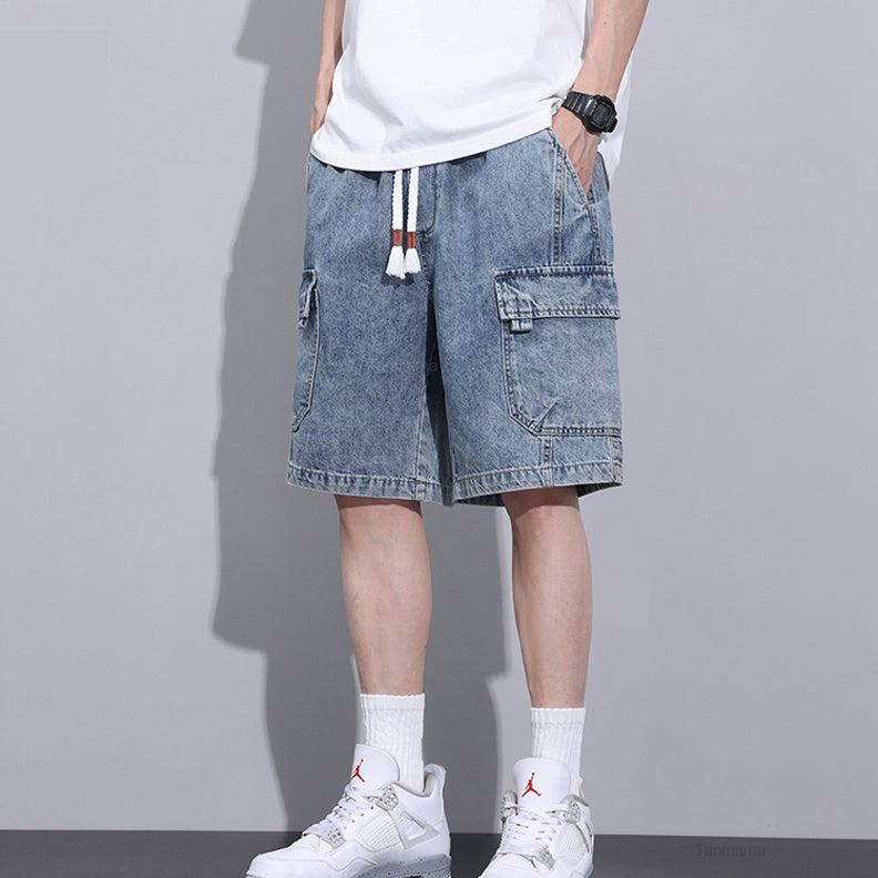 A person wearing a white T-shirt, mens denim shorts with an elastic waist and drawstrings, white crew socks, and white sneakers stands against a plain gray background. The persons head and upper body are out of frame.