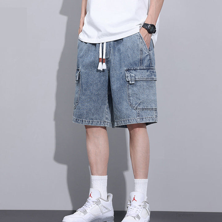 A person wearing a white T-shirt, mens denim shorts with an elastic waist and drawstrings, white crew socks, and white sneakers stands against a plain gray background. The persons head and upper body are out of frame.