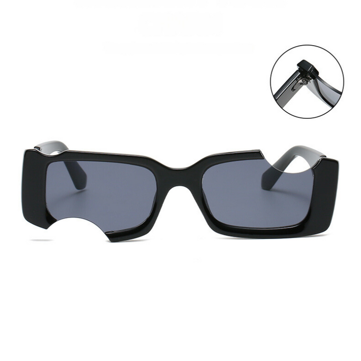 Rectangular black avant-garde sunglasses with dark lenses and a unique circular cutout on the left lens. An inset highlights the hinge detail on the arm. These irregular sunglasses offer eye-catching style and reliable UV400 protection.