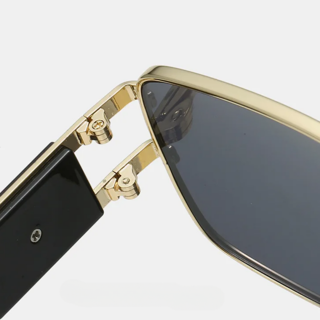 Close-up view of the hinge connecting the gold and black arm of these bold sunglasses to the dark-tinted lens frame, showing the detailed metal hardware found in premium metal frames.