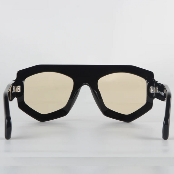 A pair of black, geometric-frame sunglasses crafted from acetate with slightly yellow-tinted lenses and UV400 protection, shown from the front on a plain white background.