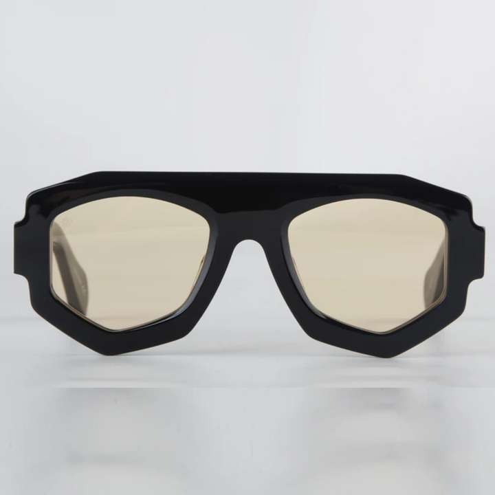 Black geometric sunglasses with thick, angular acetate frames and light tan-tinted lenses, offering UV400 protection. Displayed against a plain, light background.