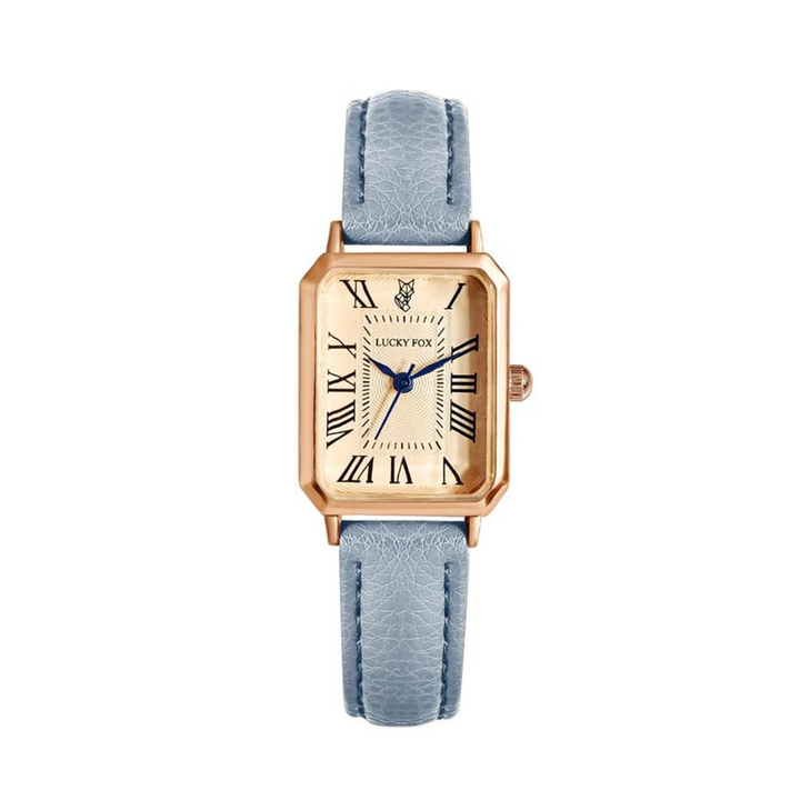 A rectangular face watch with a gold case, cream dial, blue Roman numerals, blue hands, and a small fox logo at the top. It features a textured light blue genuine leather strap for added elegance.