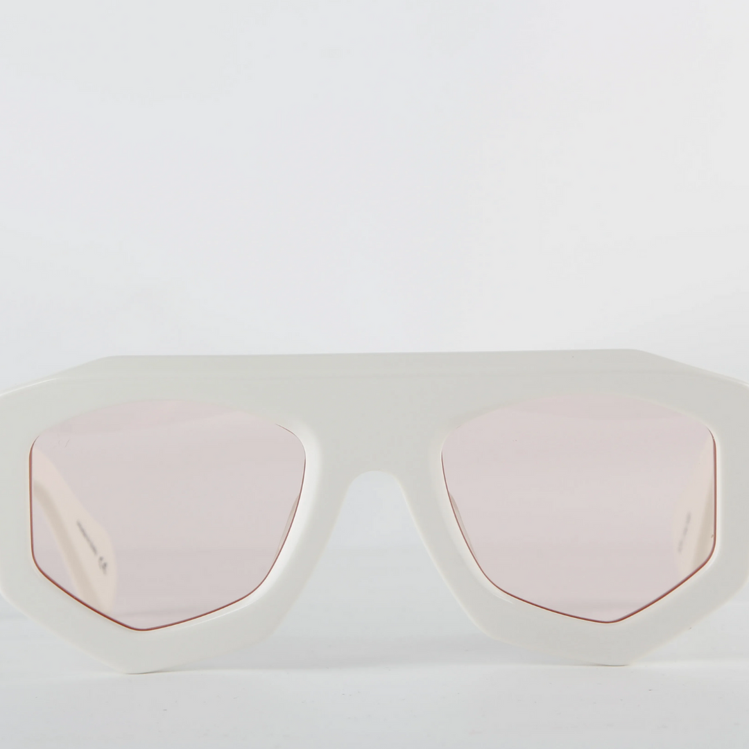 White oversized sunglasses with a thick geometric acetate frame and light pink tinted lenses, offering UV400 protection. Displayed against a plain white background.