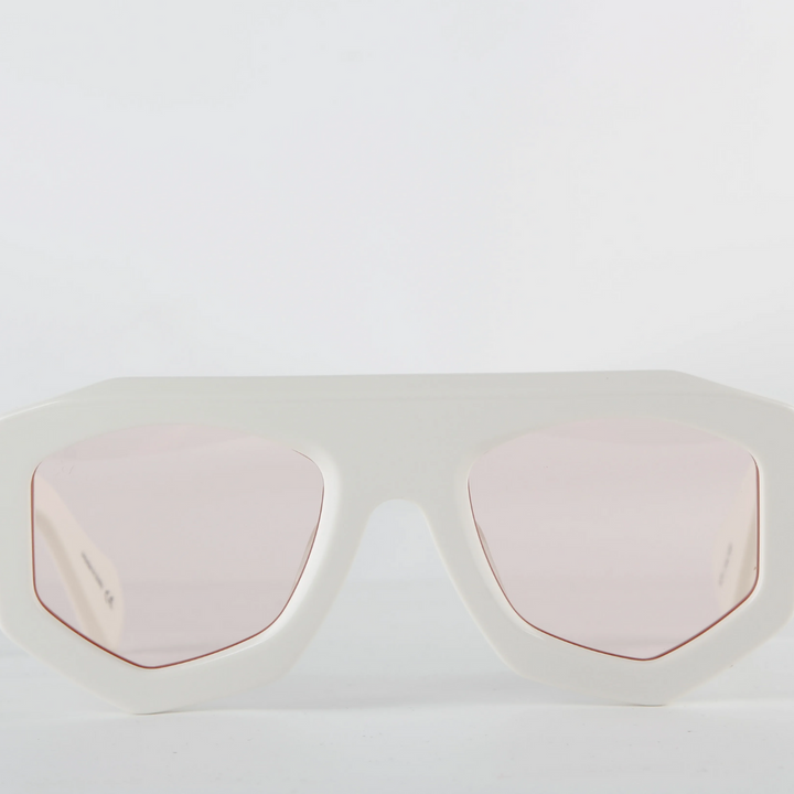 White oversized sunglasses with a thick geometric acetate frame and light pink tinted lenses, offering UV400 protection. Displayed against a plain white background.