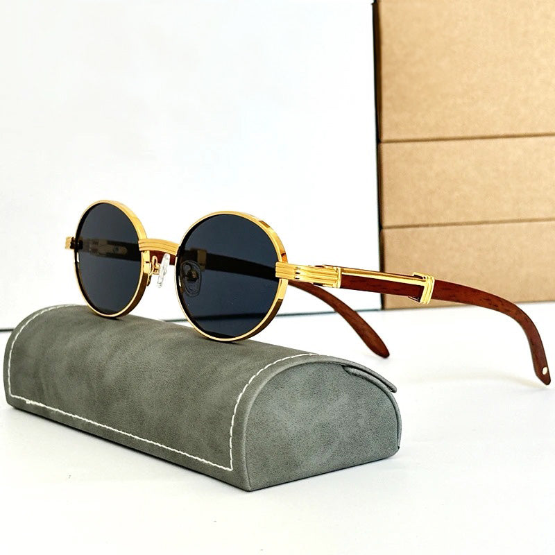 Vintage round sunglasses with gold frames and dark lenses rest on a gray, velvet-like case. Featuring wooden temples that are slightly curved, these shades offer both style and UV400 protection. A stack of tan boxes decorates the white background.