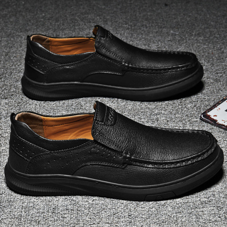 A pair of Men's Cowhide Leather Slip-On Shoes with soft, textured soles and brown inner lining, displayed side by side on a gray textured surface.