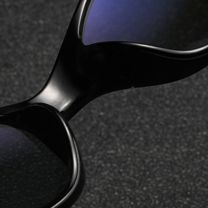 Close-up of cycling sunglasses with a sleek rectangular frame and dark, reflective UV400 protection lenses, resting on a textured dark surface.