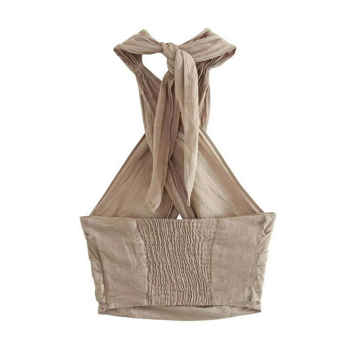 A beige, sleeveless crop top with a chic halter collar and smocked front panel. Wide straps tie into a bow at the neck, while the lightweight, textured fabric makes it perfect for effortless summer style.
