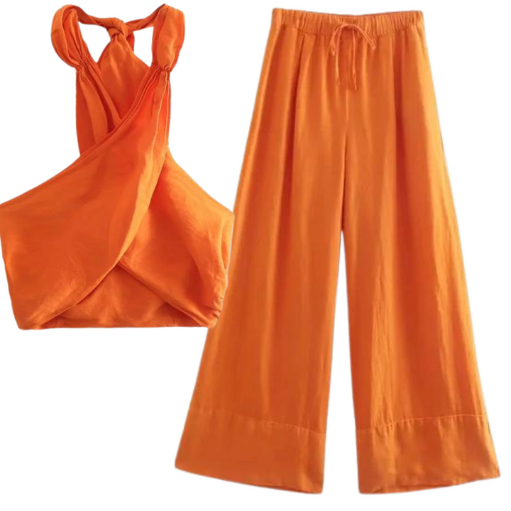 A two-piece orange outfit featuring a chic halter collar, sleeveless criss-cross crop top, and high-waisted wide-leg pants made of lightweight fabric—perfect for effortless summer style.