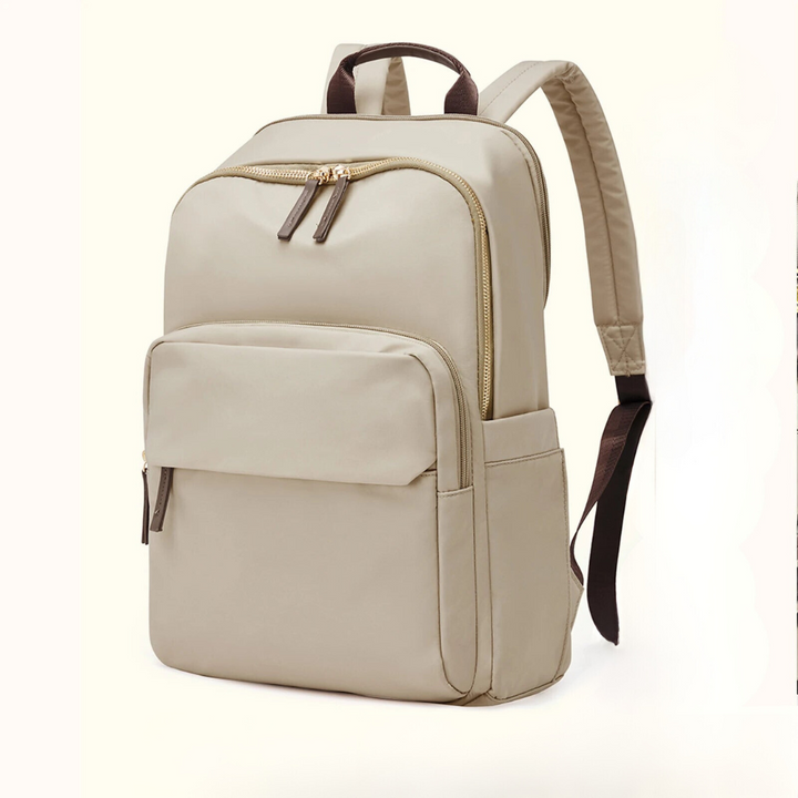 A beige, lightweight durable backpack with gold zippers, a large front pocket, two side pockets, padded shoulder straps, and a laptop compartment, displayed against a plain light background.